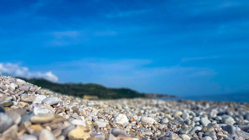 Surface level of stones on beach against blue sky