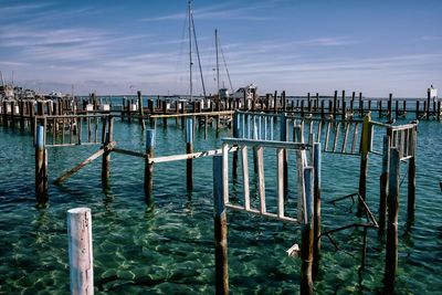 Wooden posts in sea against sky