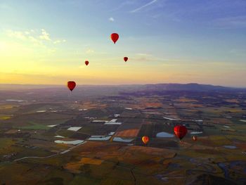 Hot air balloons flying over landscape against sky during sunset