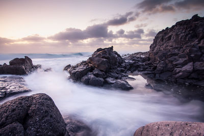 Scenic view of rock formations by sea against sky during sunset