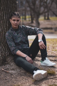 Portrait of girl sitting against tree trunk