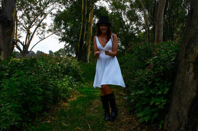 Full length portrait of woman standing against plants