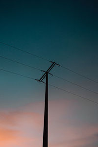 Low angle view of silhouette electricity pylon against sky at sunset