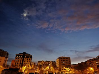 Low angle view of illuminated buildings against sky at sunset