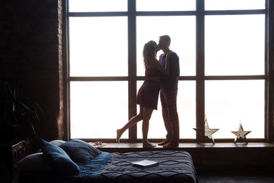 Woman standing on bed at home