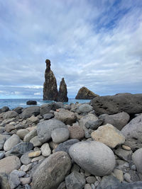 Stone stack on rocks by sea against sky