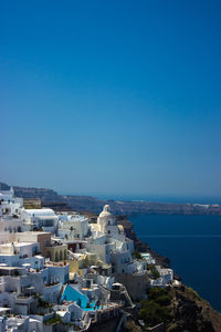 High angle view of cityscape by sea against clear sky