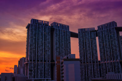 Low angle view of skyscrapers against cloudy sky
