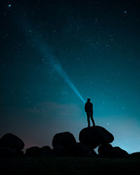 Low angle view of silhouette man standing against star field