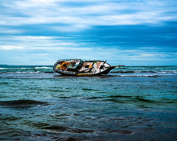 Abandoned boat in sea against sky