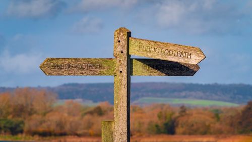 Information sign on wooden post on field against sky