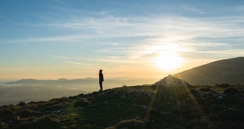 Silhouette man standing on mountain against sky during sunset