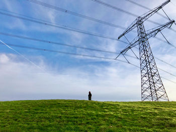 Low angle view of woman standing on hill against sky