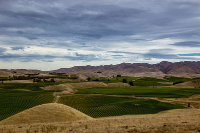 High angle view of crop field against mountains and cloudy sky