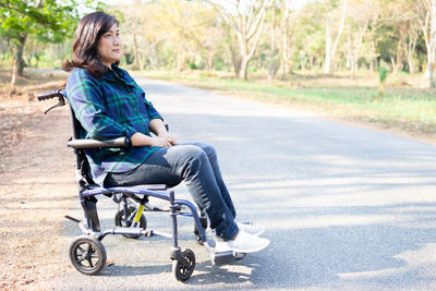 Full length portrait of teenage girl sitting on road