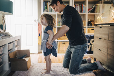 Father dressing daughter in living room