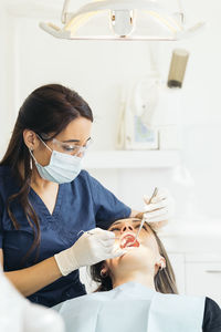 Female dentists examining woman teeth at hospital