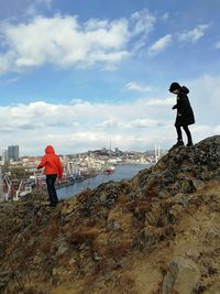 Rear view of man standing on rock against sky