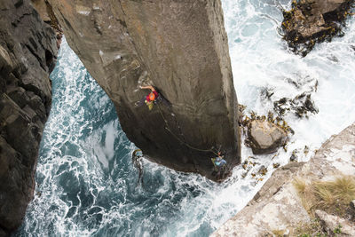 Rock climber chalks up as he climbs the totem pole out of the ocean in cape hauy, tasman national park, tasmania, australia.