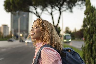 Smiling blond woman with backpack contemplating at sunset