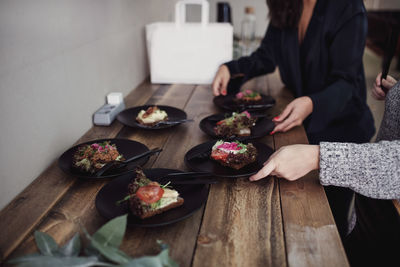 Midsection of female colleagues standing with food plates at table in workshop