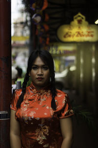 Young woman in traditional clothing looking away while standing by pole