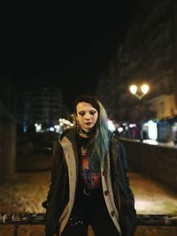 Portrait of beautiful woman in city at night