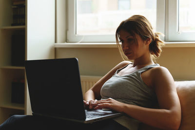 Young woman using mobile phone at home