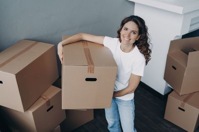 Portrait of smiling young woman holding cardboard box