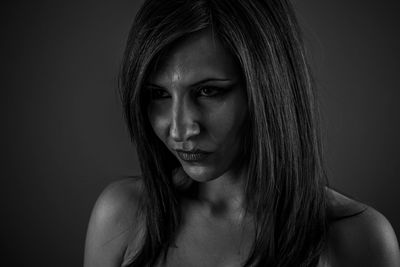 Close-up portrait of young woman against black background