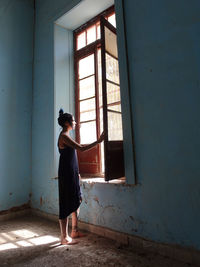 Side view of young woman standing against wall