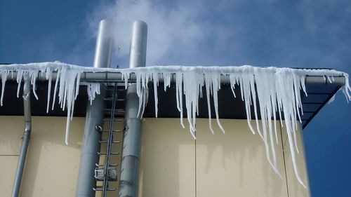 Low angle view of icicles on roof against sky