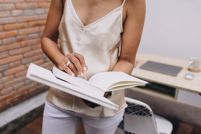 Black woman reading and writing notes in a notebook standing next to a desk