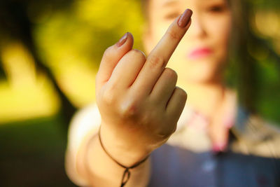 Close-up hand of woman showing obscene gesture