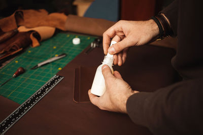 Leatherworker use glue. tanner works with leather, small business, production. closeup