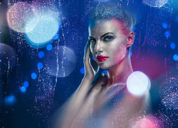 Portrait of naked woman with glitter against blue background