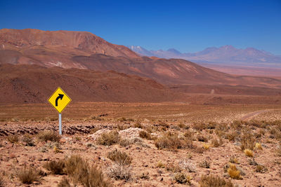 Road sign in desert against sky