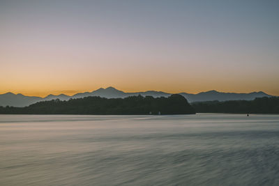 Scenic view of lake against clear sky during sunset