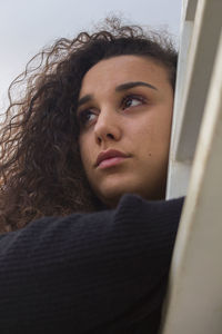 Close-up of beautiful young woman with curly hair looking away