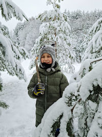 Portrait of man covering snow covered tree