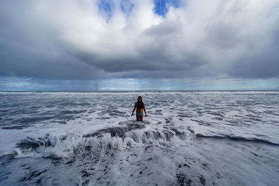 Rear view of people on sea shore against sky