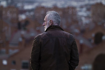 Rear view of adult man looking at city skyline of madrid, spain, during sunset