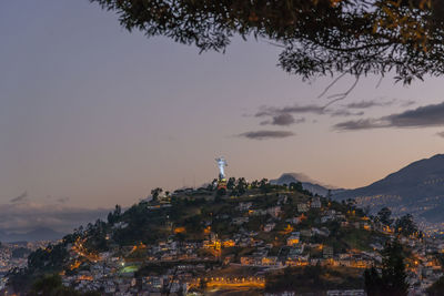 Illuminated buildings in city against sky during sunset