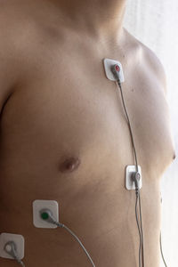 Midsection of shirtless man with medical equipment