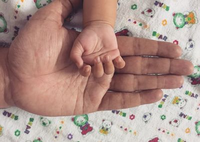 High angle view of person and baby hand on bed