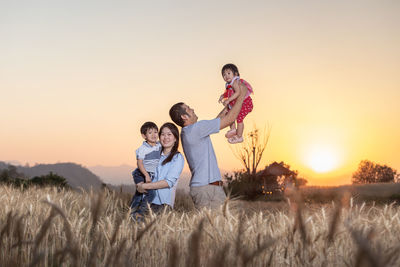 Happy family standing on land against sky