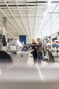 Businesswoman with colleague operating machinery in industry