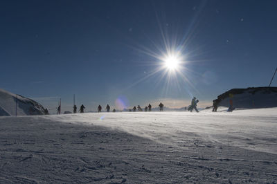 Group of people on snow covered land against bright sun
