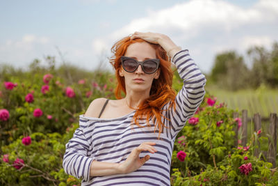 Beautiful young woman near rose bush