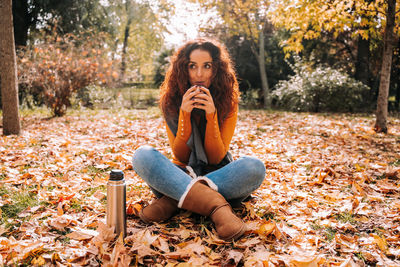 Portrait of young woman sitting on autumn leaves